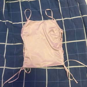 Ljusrosa satin korsett från Bikbok - Supersöt ljusrosa korsett-topp från Bikbok i satin med smala axelband och snörning på sidorna. 