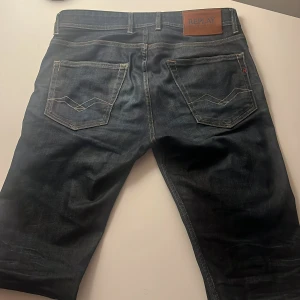 Replay mörkblå jeansbyxor - Snygga mörkblå jeans från Replay med klassisk femficksdesign och kontrastsömmar. Byxorna har en rak passform och detaljerad logopatch i läder baktill. Materialet är slitstarkt jeans och färgen har en cool tvättad look.