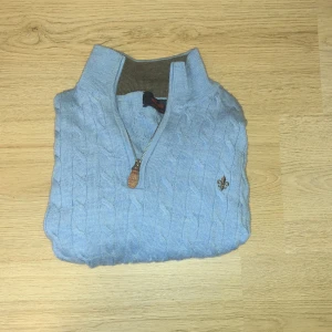 Ljusblå stickad tröja Morris  - Snygg ljusblå stickad tröja från Morris i 100% merinoull. Tröjan har kabelstickat mönster, halvzip. Den är använd ca 1-2 gånger. Och köpte den på Morris hemsida för 1500( tror jag ). Pris kan diskuteras. Och jag svarar på allt. Är öppen för byten.