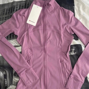Ljus/rosa träningsjacka från Lululemon - Snygg lilarosa träningsjacka från Lululemon. Perfekt till träning eller idrott i skolan. Kan posta den 20de november❤️