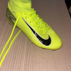 Neongula, gröna Nike fotbollsskor Flyknit - Säljer ett par sjukt snygga neongula Nike fotbollsskor med svart swoosh och coola silverdetaljer. Skorna har hög strumpkrage, snörning och är tillverkade i lätt och ventilerande flyknit-material. Perfekta för dig som vill sticka ut på planen! De lyser på planen. De är storlek 40. Det är PRO. 