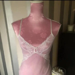  spetsig linnetopp med smala band - Säljer en linnetopp med tunna axelband och vacker vit spetsdetalj framtill. Toppen är figurnära och har en feminin v-ringning med spetskant. Materialet är lätt och genomskinligt, perfekt för att skapa en söt och romantisk look.