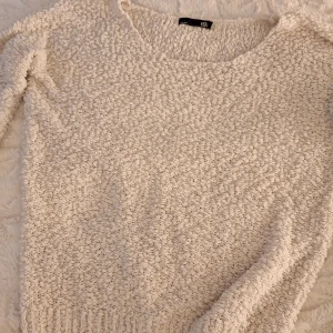 Beige stickad tröja från 157 - Mysig beige stickad tröja från 157 med fluffig struktur och rund halsringning. Perfekt för lager-på-lager och chill dagar. Långärmad modell med ribbade muddar nedtill för extra komfort.