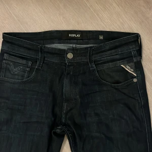 Replay svarta jeansbyxor slim fit - Svarta jeansbyxor från Replay med klassisk femficksdesign och snygga detaljer som Replay-logga på fickan och läderpatch baktill. Slim fit-modell med smal passform och raka ben. Materialet är stretchigt jeans för skön komfort. Passar mig bra som är 189 cm lång. Hör av er vid funderingar!