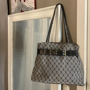 Grå axelväska med bälte - Snygg grå axelväska med svart mönster och coolt bältdetalj runt väskan. Materialet är tåligt tyg med detaljer i syntet. 💗🙌🏼