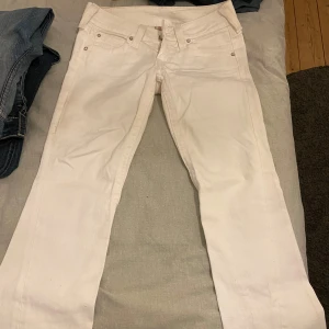 COOLA LOW WAIST VITA TRUE RELIGION JEANS BOOTCUT - Supersnygga low waist true religion jeans med diamantstenar på bakfickorna och även på andra detaljer. Sitter lite konstigt på mig därför jag säljer, storlek W 28 och uppsydda ben till L 30, sitter perfekt längd på mig som är 157. Köpte dem second hand i Wien 2024 och har ingen aning om vad fläcken bak kommer från, försöker verkligen ta bort den i tvätten. 