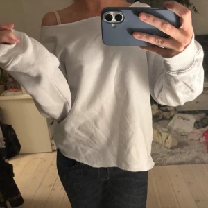 Vit offshoulder tröja - Säljer en vit sweatshirt med offshoulder-modell och långa ärmar. Tröjan har en loose passform och är tillverkad i mjukt bomullsmaterial. 