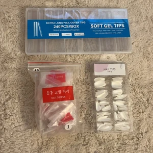 Stort kit med lösnaglar i olika former - Säljer tre olika förpackningar med lösnaglar: en ask med 240 extra långa genomskinliga soft gel tips, en påse med 500 vita nageltippar och en ask med 100 vita nageltippar i olika storlekar. Perfekt för att fixa snygga naglar hemma. Det har tagits tippar från alla förpackningar men det är 40-90% kvar i dom olika!