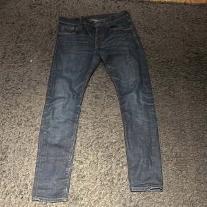 Mörkblå jeans med smal passform - Säljer ett par mörkblå jeans med klassisk femficksdesign och smal passform. Jeansen har snygga kontrastsömmar och är tillverkade i ett slitstarkt denimtyg. Perfekta för dig som gillar en stilren och enkel look.