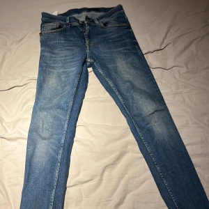 Blå skinny jeans från Levi's - Säljer ett par klassiska blå skinny jeans från Levi's med snyggt slitna detaljer på låren och knäna. Jeansen har fem fickor, dragkedja och knapp i midjan. Perfekta för dig som gillar en tajt passform och stilren look.
