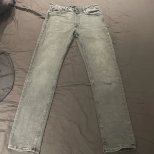 Grå jeansbyxor i straight fit, 29/32 - Snygga grå jeansbyxor med klassisk femficksdesign och raka ben. Byxorna har en straight fit och normal passning, med subtil tvättad look. Perfekt för dig som gillar enkel och stilren denim. Storlek 29/32. Nypris runt 900 mitt pris 300. Bara och höra av er om ni har några frågor!