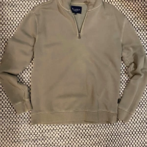 Olivgrön half zip tröja Bondelid - Olivgrön långärmad tröja från Bondelid med half zip-dragkedja vid halsen. Tröjan har ribbade muddar och är tillverkad i mjuk bomull, perfekt för chill dagar. Snygg och enkel design som funkar till jeans eller joggers.                                                                                    Storlek-S