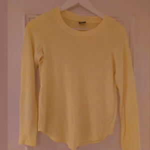 Gul långärmad tröja från Gina Tricot - En enkel och fräsch gul långärmad tröja från Gina Tricot i storlek XS. Tröjan har rund halsringning och är gjord i mjuk bomull, perfekt för lager på lager eller som den är. Snygg och stilren basic som passar till allt.