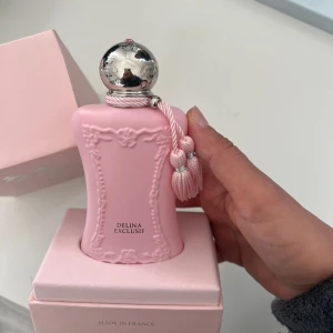 Delina Exclusif Parfym Pink Edition - Lyxig parfym i en snygg rosa flaska från Parfums de Marly. Delina Exclusif är tillverkad i Frankrike och levereras i en elegant förpackning. Perfekt för dig som vill sticka ut med en exklusiv doftaccessoar.