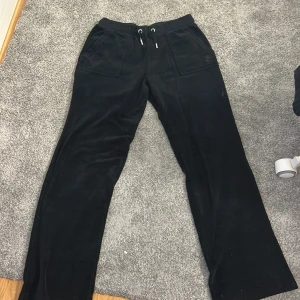 Svarta mjukisbyxor Juicy Couture - Svarta mjukisbyxor från Juicy Couture med bred resår och snörning i midjan. Byxorna har raka ben, stora fickor fram och bak med silverfärgade knappar. Mjukt och skönt material som ger en chill vibe.(frakten inkluderas i priset) och priset kan diskuteras 