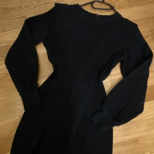 Svart långärmad klänning från DIVIDED - Säljer en svart långärmad klänning från DIVIDED i storlek XS. Klänningen har en rund halsringning och markerad midja som ger en snygg siluett. Materialet är mjukt och bekvämt, perfekt för dig som gillar enkel och stilren design.