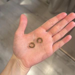 Guldiga små creoler örhängen - Säljer ett par stilrena små creoler i guldfärgad metall. De är runda och har en enkel, klassisk design som passar till många olika stilar. Perfekta om du gillar minimalistiska smycken och vill ha något som funkar varje dag.