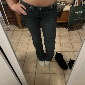 Mörkblå bootcut jeans från Nelly - Snygga mörkblå jeans från Levi's med klassisk bootcut passform och låg midja. Jeansen har fem fickor, knapp och dragkedja framtill samt slitningar för en cool look. Perfekta för dig som gillar en tidlös stil med lite edge.