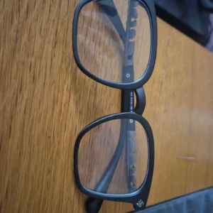 Svarta glasögon från Chrome Hearts - Säljer ett par svarta glasögon från Chrome Hearts med rektangulära bågar och coola detaljer i silver på skalmarna. Märkesloggan syns tydligt på sidan och bågarna har en stilren, modern vibe. Perfekt för dig som vill ha en edgy look.