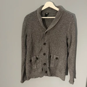 H&M kofta - Tja säljer denna H&M kofta i mörk grå färg. Den är u mycket gott skick och sitter som en perfekt M. Den är riktigt snygg och passar perfekt till vintern. Hör av er för fler frågor!