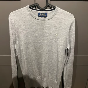 Grå stickad tröja Polo Ralph Lauren  - Snygg och skön polo Ralph lauren tröja. Med ett material som liknar Kashmir/merinoull. Sitter slimmat och passar upp till runt 165 skulle jag säga. Storlek 14-16 men passar också mindre. Köpt på nk för runt 1800kr