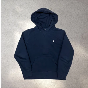 Mörkblå hoodie från Polo Ralph Lauren - Snygg mörkblå hoodie från Polo Ralph Lauren med klassisk broderad logga på bröstet. Tröjan är i bra skick, något urvtvättad. Inga hål eller liknande. Skickar snabbt efter att du har beställt✅📦L 14-16 är samma som xs i herr storlek😁