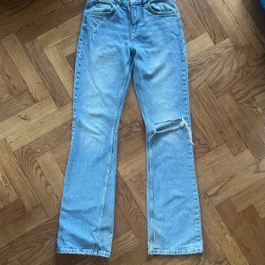 Ljusblå jeans från Perfect Jeans - Snygga ljusblå jeans från Perfect Jeans i rak modell med hög midja. Jeansen har klassisk femficksdesign och en cool sliten detalj med hål på ena knät. Perfekt för dig som gillar en avslappnad och trendig look.