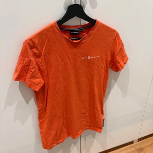 Orange t-shirt från Sail Racing, XS - Fräsch orange t-shirt från Sail Racing i storlek XS. T-shirten har korta ärmar, rund hals och en vit logga tryckt på bröstet samt ett mindre tryck i nacken. Materialet är mjuk bomull. Perfekt för dig som gillar sportig och enkel stil. Mycket bra skick använd ungefär 3 gånger och priset kan ju diskuteras 