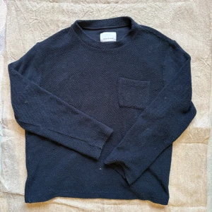 Mörkblå stickad tröja Samsoe Samsoe - Snygg mörkblå stickad tröja från Samsoe Samsoe med rund hals och en liten bröstficka. Tröjan har långärmade och en enkel, clean design som passar perfekt till jeans eller chinos. Perfekt för dig som gillar stilrena plagg med lite edge.