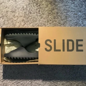 Adidas Yeezy Slide Onyx - Säljer dessa helt nya yeezy slides för bra pris, aldrig använda. Lådan är lite sönder. Storlek 42 men passar även 40 och 41