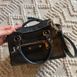 Svart handväska med guldiga detaljer -  svart handväska med både handtag och axelrem, samt en dragkedja framtill och upptill. Pris kan diskuteras !