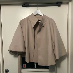Beige pnchokappa från missäy - Beige poncho från missäy i storlek S!🥰🥰 knappen vid halsen sitter lite löst och den har en liten grå fläck på baksidan (se bild)