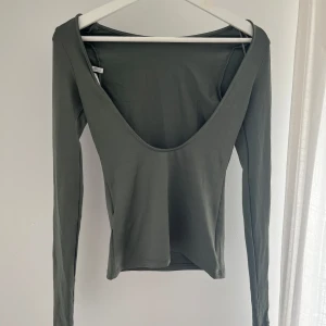 Grön långärmad topp med öppen rygg - Snygg grön långärmad topp med djup, öppen rygg och tight passform. Väldigt mjukt och stretchigt material. Mycket bra skick😊