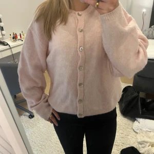 Ljusrosa kofta från Gina Tricot - Superfin ljusrosa kofta från Gina Tricot med rund halsringning och knappar framtill. Koftan är stickad i mjukt material och har långa ärmar med ribbade muddar.