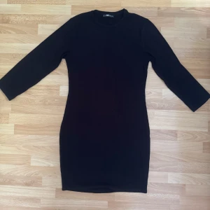 Svart ribbad klänning FB Sister - En svart, ribbad klänning från FB Sister i storlek XL. Modellen är kort med trekvartsärm och har en rund halsringning. Klänningen har en slim passform som framhäver figuren och är tillverkad i mjuk bomull för en bekväm känsla. Förminskad och är som M. Bröst 90cm. Sydde upp ärmarna till trekvart längd.