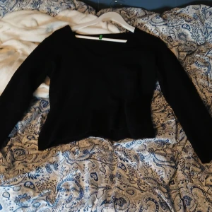 Svart stickad tröja från Benetton - Svart stickad tröja från United Colors of Benetton med v-ringad hals och långärmad design. Tröjan har en klassisk, enkel look och är mjuk och skön att bära. Perfekt för dig som gillar stilrena och tidlösa plagg.