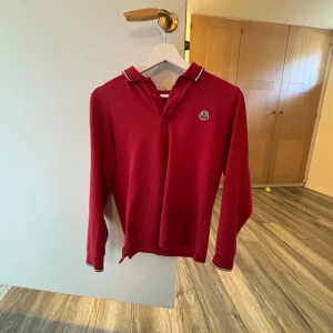 Röd moncler pikétröja - En fin moncler pikétröja i fint skick, säljer denna för lågt pris pga ett litet hål som ni ser på bild två, men hålet syns inte när man bär den, skriv gärna om ni har några frågor