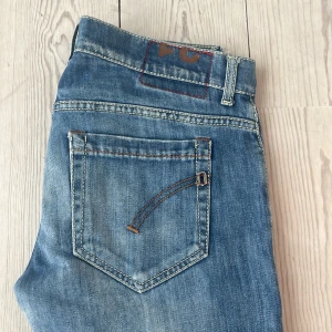 Blå jeans från Dondup, storlek 31 - Snygga blå jeans från Dondup i klassisk tvätt med raka ben och normal passform. Jeansen har fem fickor, ljusa slitningar och detaljerade sömmar på bakfickan. Tillverkade i bomull för en skön känsla och stilren look.