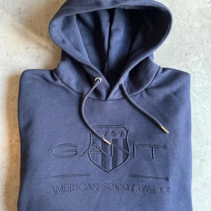 Ny Mörkblå hoodie från GANT - Snygg mörkblå hoodie från GANT Helt oanvänd. Storlek L men passar som M.