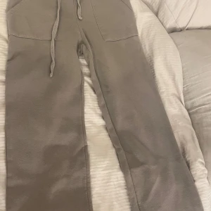 Beige mjukisbyxor med snörning - Säljer ett par beige mjukisbyxor med bred resår i midjan och snörning framtill. Byxorna har stora fickor fram och en bakficka. Sköna och avslappnade, perfekta för chill dagar. Tillverkade i mjukt bomullsmaterial.