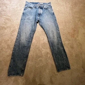 Blå jeans från Tiger of Sweden - Snygga blå jeans från Tiger of Sweden med klassisk femficksdesign och raka ben. Jeansen har en ljus tvätt och är tillverkade i bomull. Dom är inte andvända något speciellt mycket. Dom är i storlek 31/32. Skicket är utmärkt, dom ser lite mörkare ut vid benen än dom är.