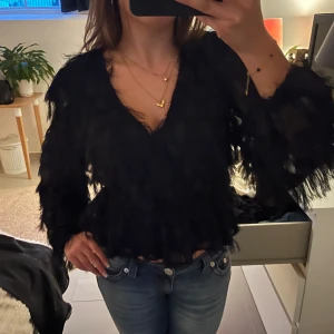 Fjäderblus gina tricot  - Svart blus från Gina tricot med fjädrar. Använd fåtal gånger, väldigt bra sick. Storleken är m men passar s.