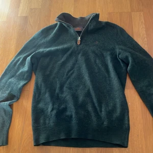 Mörkgrön merinoullströja Morris - Snygg mörkgrön tröja från Morris i mjuk merinoull. Half zip med ståkrage och diskret broderad logga på bröstet. Perfekt för dig som gillar stilrena och bekväma plagg med lite extra premiumkänsla.