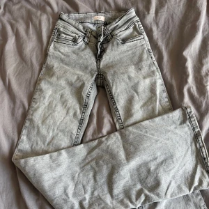 Grå bootcut jeans från Nelly - Grå jeans från Nelly med bootcut-modell och svarta kontrastsömmar. Klassisk femficksdesign och broderad bakficka. Jeansen har en ljus tvätt och är tillverkade i denim med en skön passform. Lite defekter på byxkanterna längst ner men inget man tänker på🥰