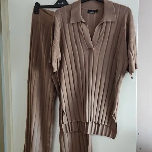 Bruna/gedigen  ribbade sättet från KappAhl - Säljer ett par bruna ribbade byxor från KappAhl i storlek M. Byxorna har en relaxed fit med breda ben och hög midja. Materialet är stickat och mjukt, perfekt för en chill och trendig look. Matcha gärna med överdelen för en komplett outfit.