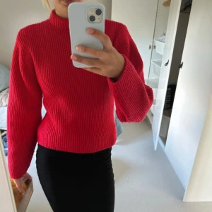 Röd ribbstickad polotröja - Säljer en snygg röd ribbstickad polotröja med hög hals och långa ärmar. Tröjan har en klassisk passform och är perfekt för dig som vill ha en färgklick i garderoben. Materialet är mjukt och skönt, perfekt för kyligare dagar. Den är pyttelite nopprig men inget som direkt märks. Perfekt till hösten och jul