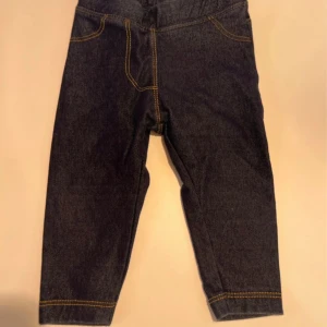 Mörkblå babyjeans med resårmidja - Mörkblå babyjeans från Lager 157 BEBE med resår i midjan och kontrastsömmar. Byxorna har klassisk femficksdesign och är tillverkade i en mjuk mix av ekologisk bomull, polyester och elastan för extra stretch och komfort.