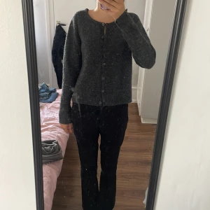 Mörkgrå kofta med knappar - Mysig mörkgrå kofta med rund hals och knäppning framtill. Tröjan har långa ärmar och en loose passform som ger en chill vibe. Materialet är stickat och känns skönt mot huden. Perfekt att slänga på sig när det är lite kyligt ute. 