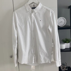 Vit skjorta från Tommy Hilfiger - Klassisk vit skjorta från Tommy Hilfiger med diskret logga broderad på bröstet. Nypris 899 kr