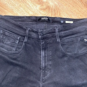 Svarta Replay Anbass jeans herr - Säljer ett par svarta Replay Anbass jeans i klassisk femficksmodell. Jeansen har en snygg, mörk tvätt och raka ben. Märkesdetaljer på fickorna och midjebandet. Perfekta för dig som gillar stilrena och bekväma jeans.